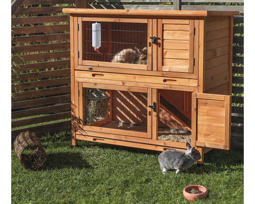 Clapier à lapin en bois à deux étages avec accessoires dans le jardin.