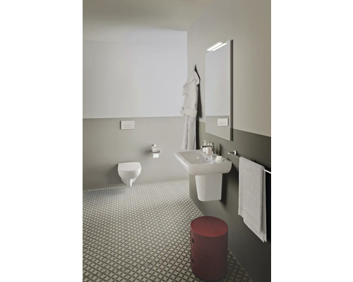 Salle de bains lumineuse avec WC suspendu, lavabo, miroir, porte-serviettes et carrelage à motifs