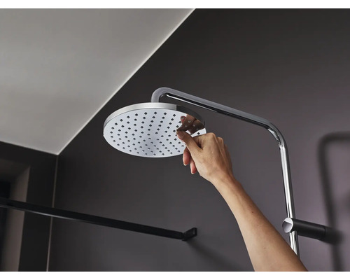 Main touchant la pomme de douche avec bras de douche dans la salle de bain