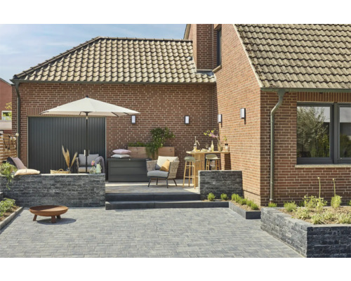 Gestalteter Gartenbereich mit Pflastersteinen, Gartenmöbeln und Beleuchtung