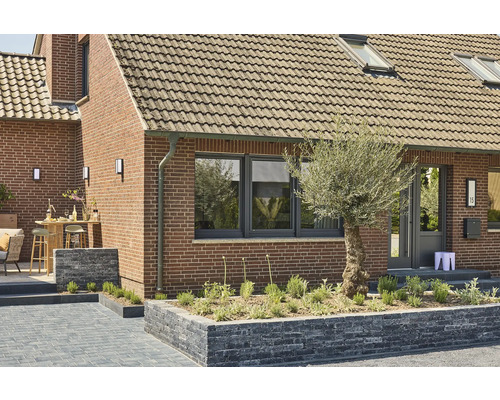 Extérieur d''une maison avec des murs en briques, des fenêtres, une porte et un aménagement paysager