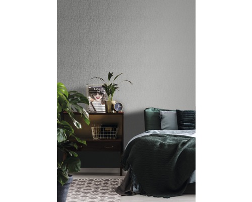 Schlafzimmer mit grauer Vliestapete, Nachttisch, Dekoration und Bett