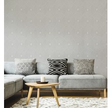 Salon avec canapé gris, coussins et papier peint à motifs géométriques