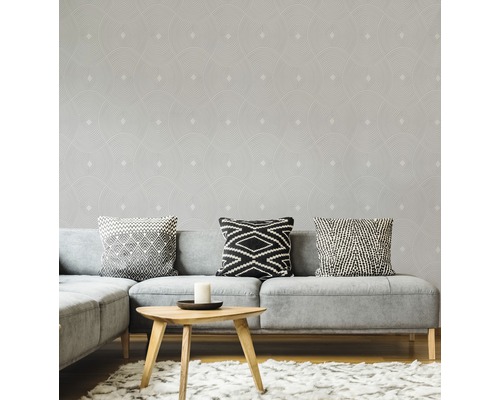 Salon avec canapé gris, coussins et papier peint à motifs géométriques