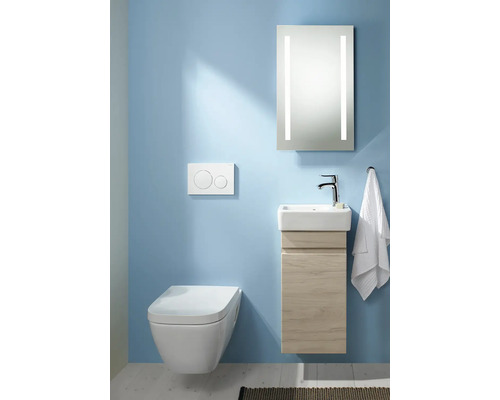 Salle de bains moderne avec WC suspendu, meuble sous-lavabo et miroir éclairé