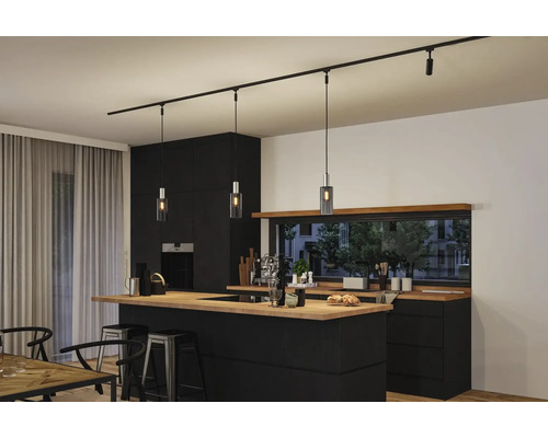Kücheninnenraum mit schwarzer Kücheninsel und daran hängender schwarzer Schienenleuchte mit Pendelleuchten
