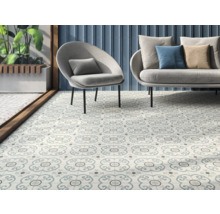 Intérieur avec des carreaux de sol décorés, un fauteuil et un canapé.