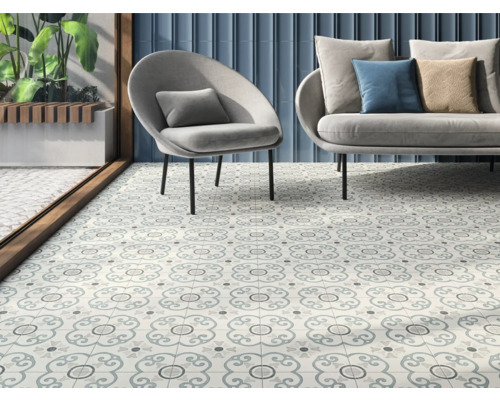Intérieur avec des carreaux de sol décorés, un fauteuil et un canapé.
