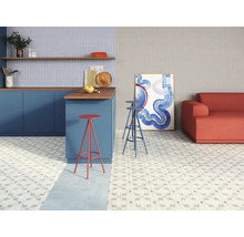 Cuisine et salon lumineux avec carrelage à motifs floraux, comptoir avec tabourets de bar et canapé.