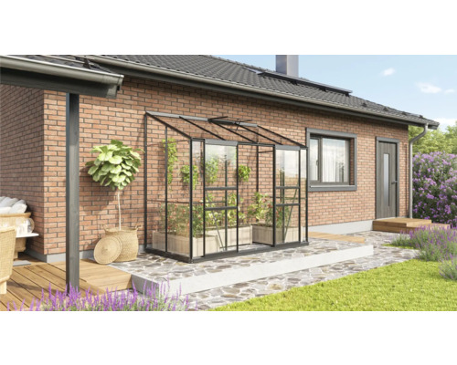 Serre avec des plantes sur une terrasse à côté d''une maison d''habitation.