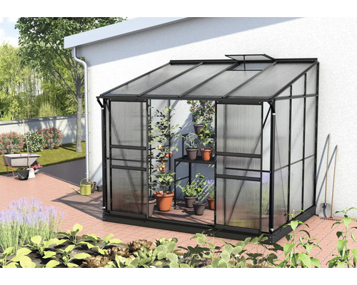 Serre adossée Vitavia Ida 5200 panneaux alvéolés 4 mm 262,1x201,4 cm noir Serre en métal et plastique sur un mur de maison avec des plantes à l''intérieur.
