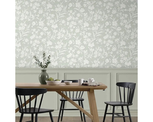 Salle à manger avec table et chaises devant un mur avec du papier peint à fleurs