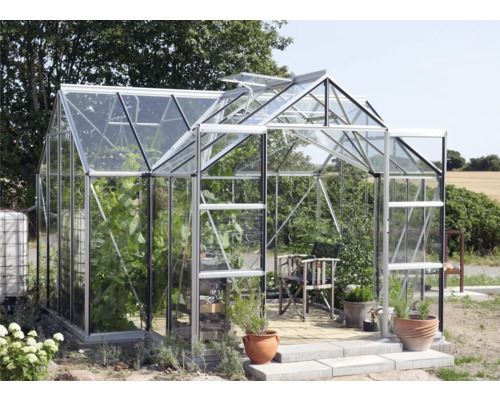 Serre avec plantes, chaise et pots dans le jardin