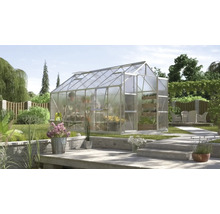 Serre aux parois transparentes dans un jardin avec plantations et terrasse
