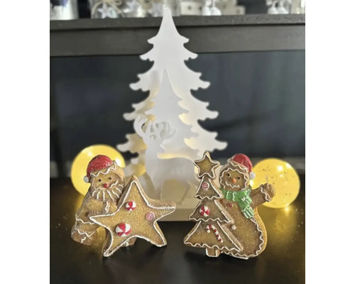 Dekorative Weihnachtsszene mit Lebkuchenfiguren und einem beleuchteten Baum mit Hirschmotiv