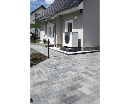 Photo extérieure d''une maison avec un chemin pavé et une pompe à chaleur air-eau installée