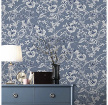 Pièce décorative avec papier peint intissé à fleurs sur le mur, commode, lampe et décorations.