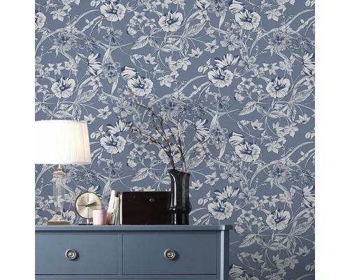 Pièce décorative avec papier peint intissé à fleurs sur le mur, commode, lampe et décorations.