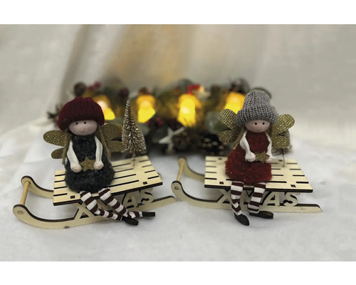 Zwei weihnachtliche Dekorationsfiguren sitzen auf Holzschlitten