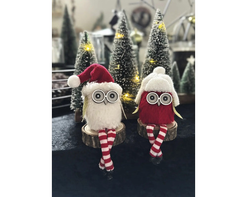 Deux hiboux décoratifs en tissu avec des bonnets de Noël et des jambes rayées sont assis sur des tranches de bois.