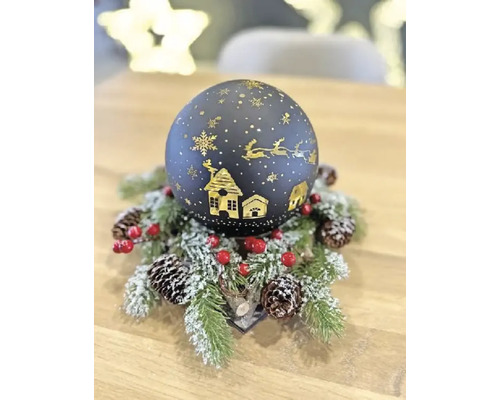 Dekoratives Arrangement mit einer Weihnachtskugel, Tannenzweigen und Tannenzapfen auf einem Tisch