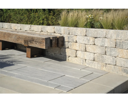 Aussenbereich mit Mauer aus Steinblöcken, Bank aus Holz und Steinbodenplatten