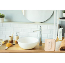 Modernes Badezimmer mit Waschbecken, Armatur und einem quadratischen, beigen Produkt auf einem Holztisch