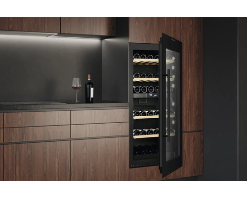 Integrierter Weinkühlschrank mit Holzeinlagen und Glasflasche auf einer Arbeitsplatte.