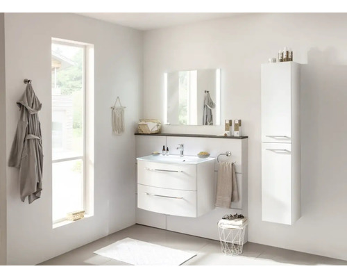 Salle de bain lumineuse avec meuble sous-lavabo, miroir, armoire haute et linge de bain.
