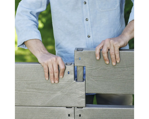 Eine Person montiert ein Zaunelement aus WPC.