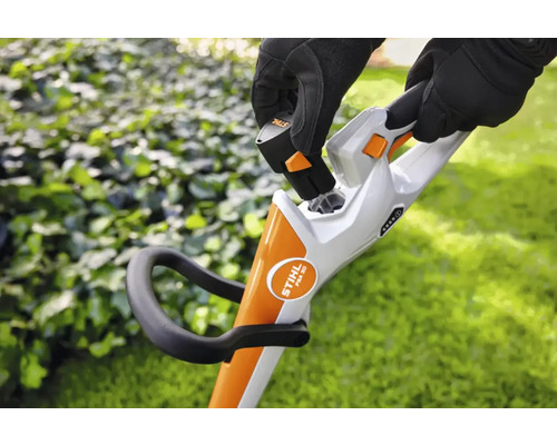 Une personne insère une batterie dans un coupe-bordures sans fil.