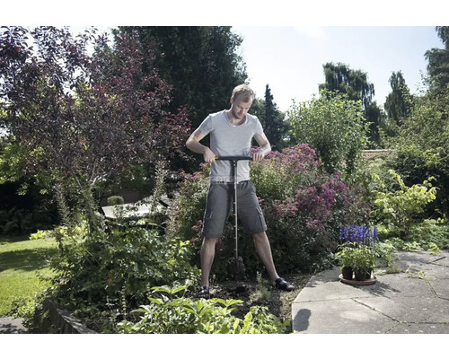 Un homme utilise un éjecteur de sol dans le jardin pour prélever des échantillons de terre.