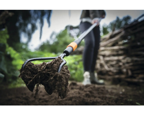 Gros plan d''une fourche à bêcher avec de la terre dans le jardin.