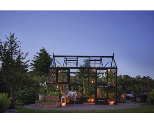 Serre avec plantes, sièges et éclairage dans le jardin.