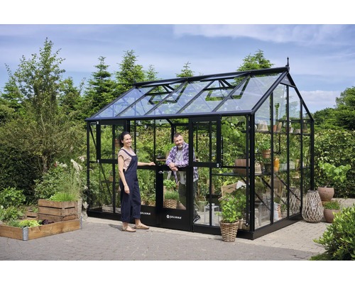 Serre en verre et métal avec deux personnes dans le jardin.