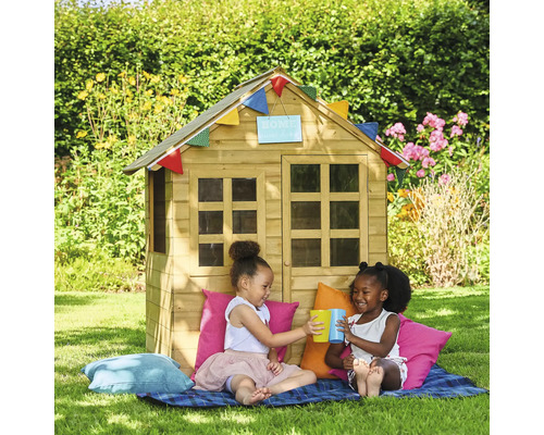 Im Garten sitzen zwei Kinder vor einem Holzspielhaus mit Fenstern und Dekoration.