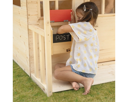 Fille à la boîte aux lettres d''une cabane de jeu en bois