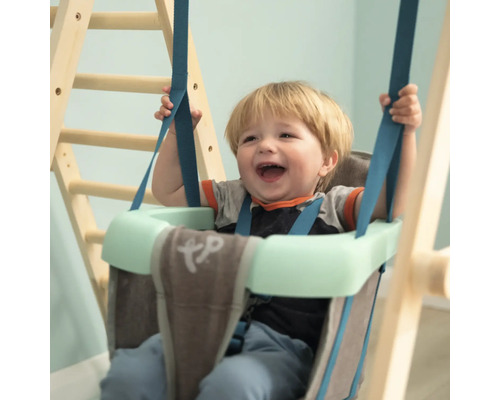 Enfant souriant dans une balançoire pour bébé avec ceinture de sécurité