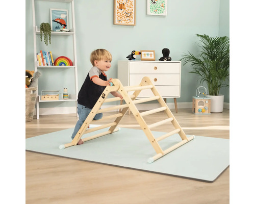 Enfant grimpant sur une structure d''escalade d''intérieur en bois sur un tapis de jeu dans une chambre d''enfant.