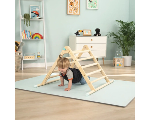 Enfant grimpant sur une structure d''escalade en bois dans une chambre d''enfant lumineuse.