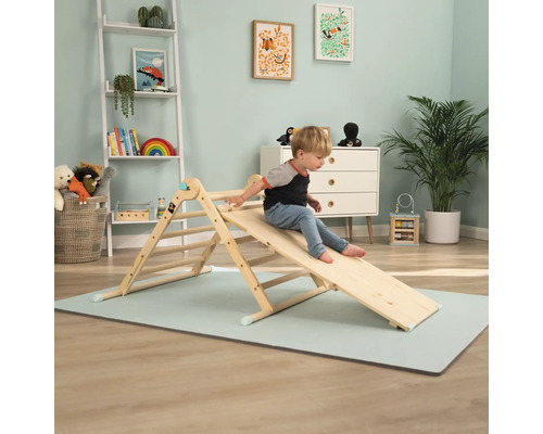 Un enfant joue sur un triangle d''escalade en bois avec toboggan dans la chambre d''enfant.