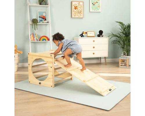 Un jeune enfant grimpe sur un jeu en bois avec toboggan dans une chambre d''enfant