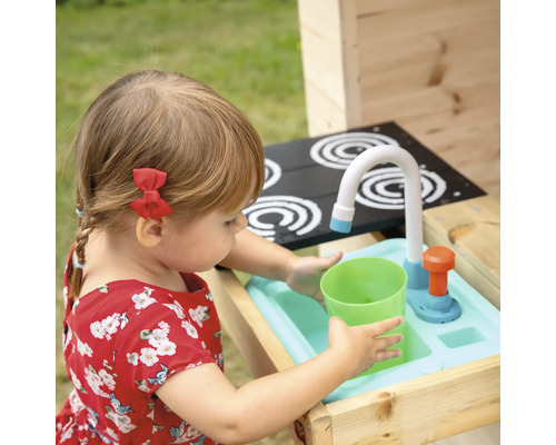 Un enfant joue avec une cuisine jouet avec évier, robinet et plaques de cuisson.