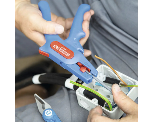 Elektriker mit Abisolierzange beim Bearbeiten von Kabeln in einer Anschlussdose.