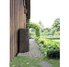 Garten mit Regentonne in Baumstammoptik neben einem Haus