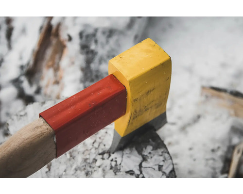 Hache avec tête jaune et protection rouge du manche sur une souche d''arbre.