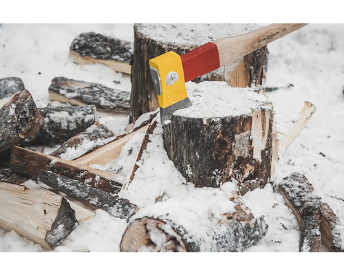 Hache coincée dans une bûche avec des morceaux de bois dans la neige