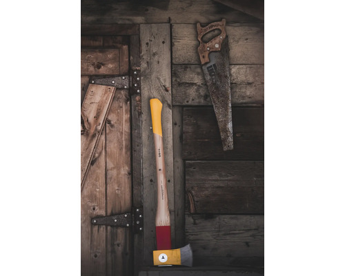 Hache et scie à main devant un mur en bois