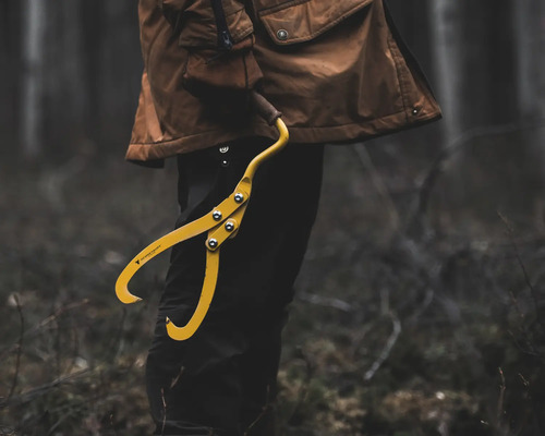 Person hält eine gelbe Hebezange im Wald.