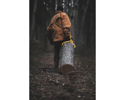Mann trägt Baumstamm mit einer Holztransportzange durch den Wald